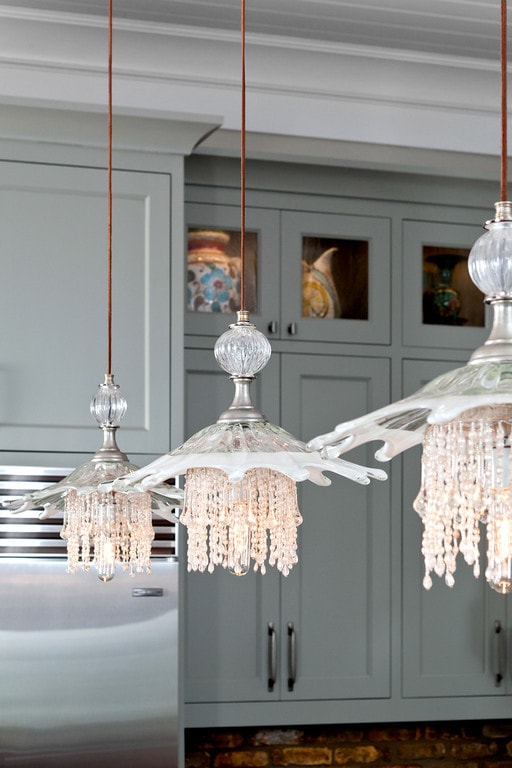 Coastal casual kitchen in waterfront home: Luna Bella jelly fish pendants, grey cabinets, exposed brick