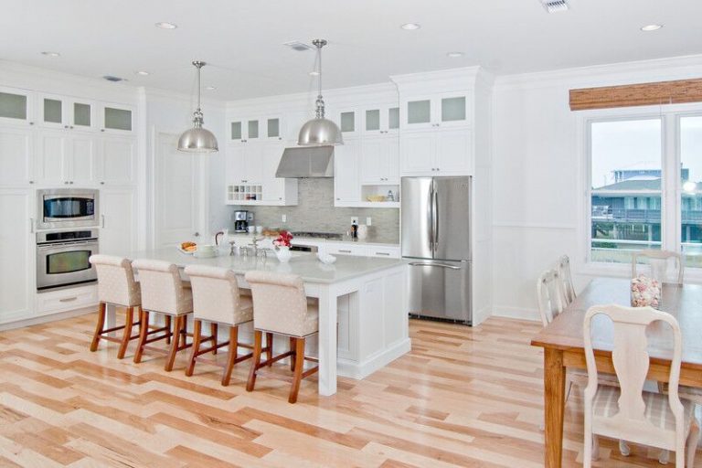 all white kitchen with stainless pendant lights and wood accents