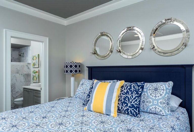 Nautical bedroom with white and blue bedding, yellow accents, and silver porthole mirrors