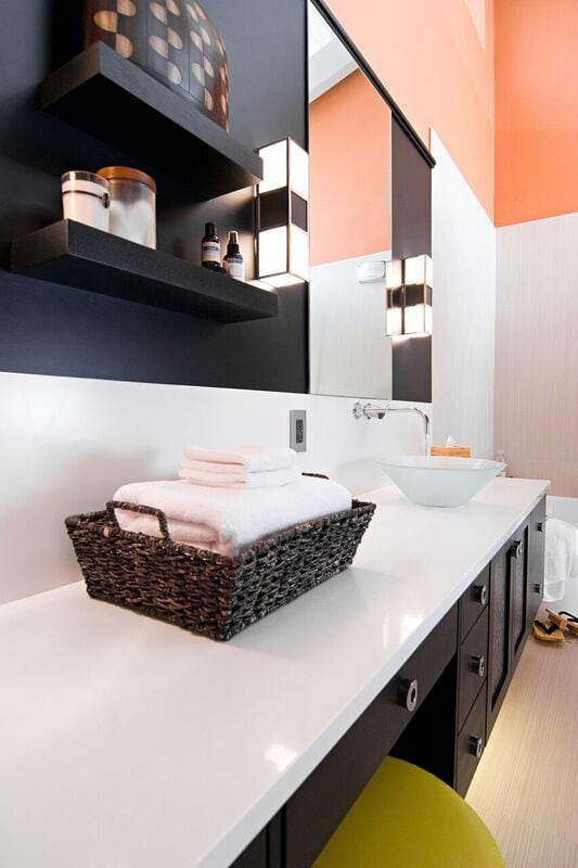 Warm modern master bath with large counter top, glass sink, and orange walls
