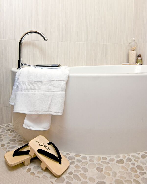 Warm modern master bath with large Neptune tub and pebble flooring