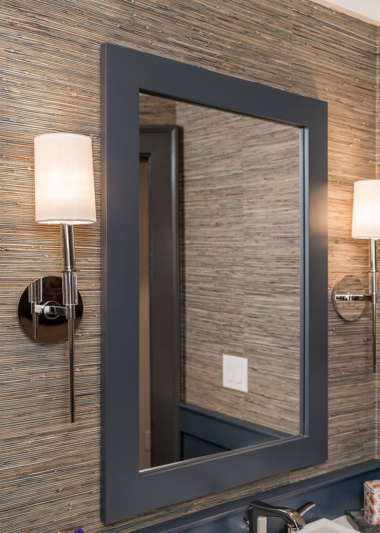 Textured wallcoverings with grey mirror and silver sconces.