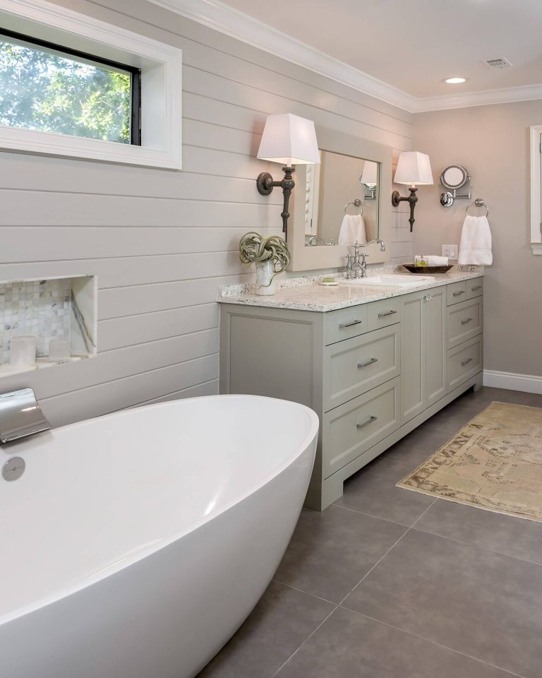 large freestanding tub with waterfall faucet neutral walls and grey tiles flooring