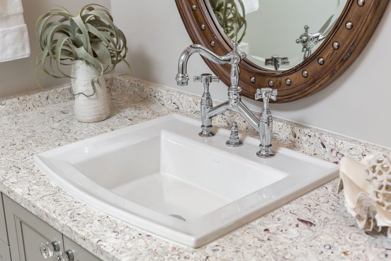 Coastal bath, countertop and sink with polished nickel faucet and wooden oval mirror with silve studs crystal cabinet pulls in Pensacola Florida