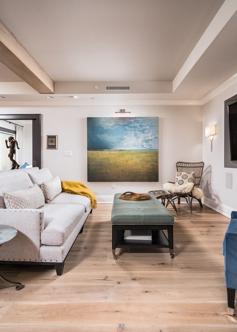 Penthouse suite turned family home with open living room with light hardwood flooring original art linen sofa blue velvet chair art