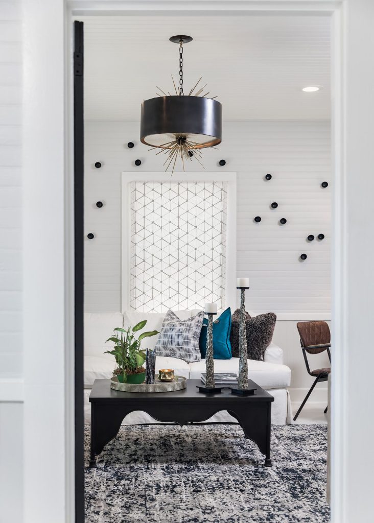 white cottage with black & white rug black lacquer coffee table white slipcover sofa black hangin light with gold startburst