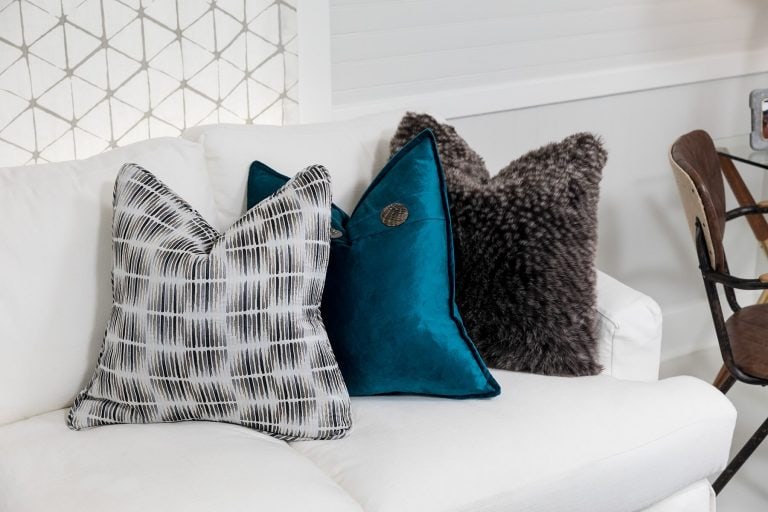white sofa with black & white pillow teal blue pillow and grey fluffy pillow