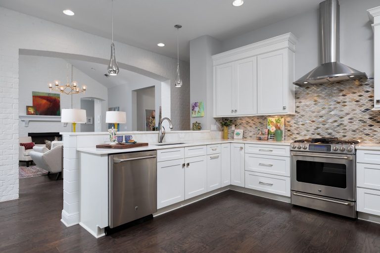 open concept kitchen and living room silver pendant lights neutral tile backsplash