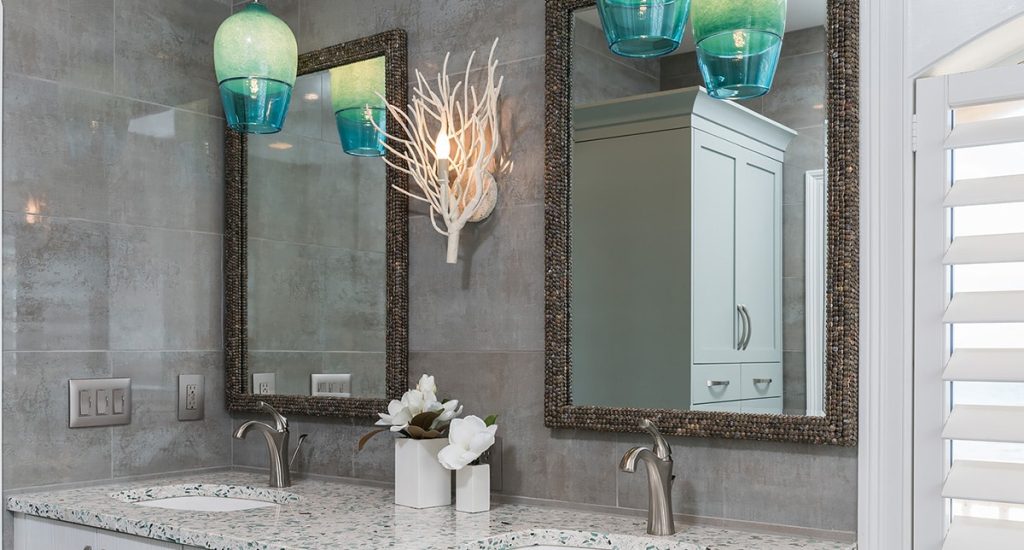 Grey tiled walls with white vanity and quartz countertops. Coral Sconce with two mirrors and two aqua pendants.