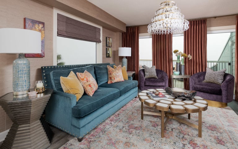 coastal condo remodel on pensacola beach living room, purple accent chairs, blue sofa, crystal chandelier, orange window treatments