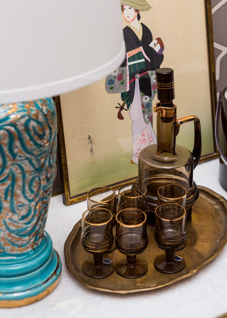 Vintage art styled next to vintage glassware and a vintage lamp on a modern day cabinet. 