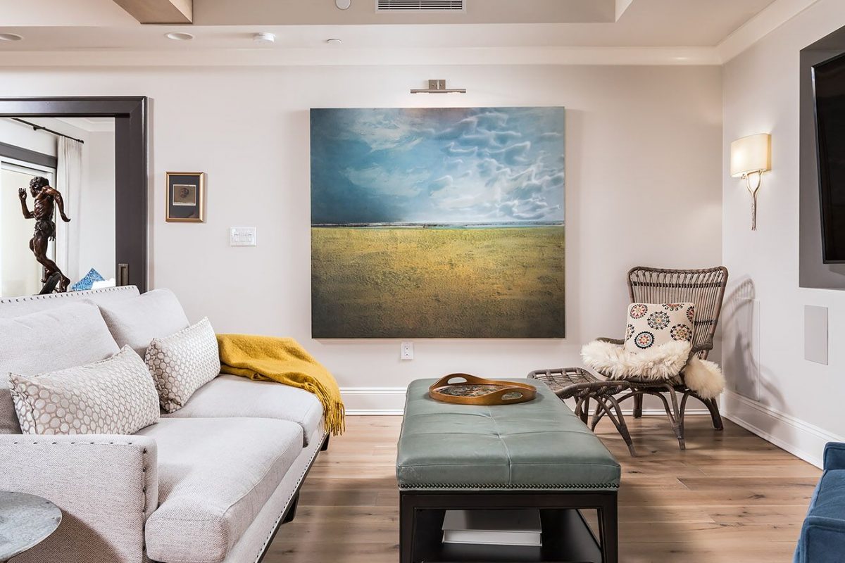 Penthouse suite turned family home with open living room with light hardwood flooring original art linen sofa blue velvet chair art